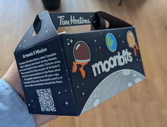 A box of Tim Horton's "moonbits", featuring two spacesuited doughnut holes ("Timbits") floating above the moon with Earth in the distance.

The text on one side reads:

Artemis II Mission

Canada will make history when Canadian Space Agency astronaut Jeremy Hansen, born and raised in the London, Ontario, area, flies around the Moon as part of Artemis II, the first crewed mission to the Moon since the Apollo missions over 50 years ago. Canada will be only the second country to ever send an astro…